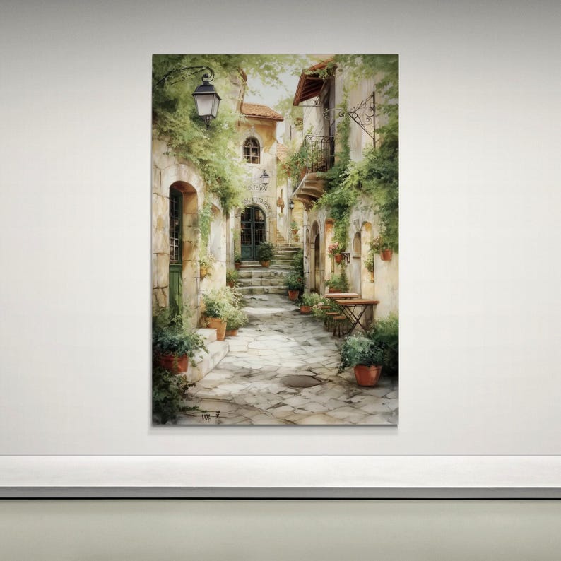 Op de afbeelding: Aquarel schilderij van een Europese straatsc&egrave;ne. De afbeelding toont een smalle geplaveide straat met gebouwen, weelderig groen en potplanten. Een vintage straatlantaarn verlicht de sc&egrave;ne en kleine tafels en stoelen staan buiten.