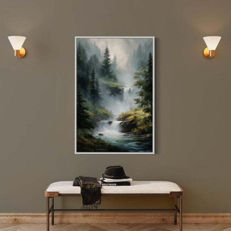 May include: A framed painting of a misty forest scene with a waterfall cascading down a rocky hillside. The painting is in a white frame and is hanging on a wall.