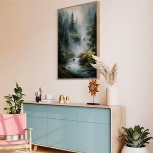 May include: A light blue dresser with three drawers and a wood top. The dresser is in a living room with a painting of a waterfall in a forest, a potted plant, and a decorative sun sculpture.