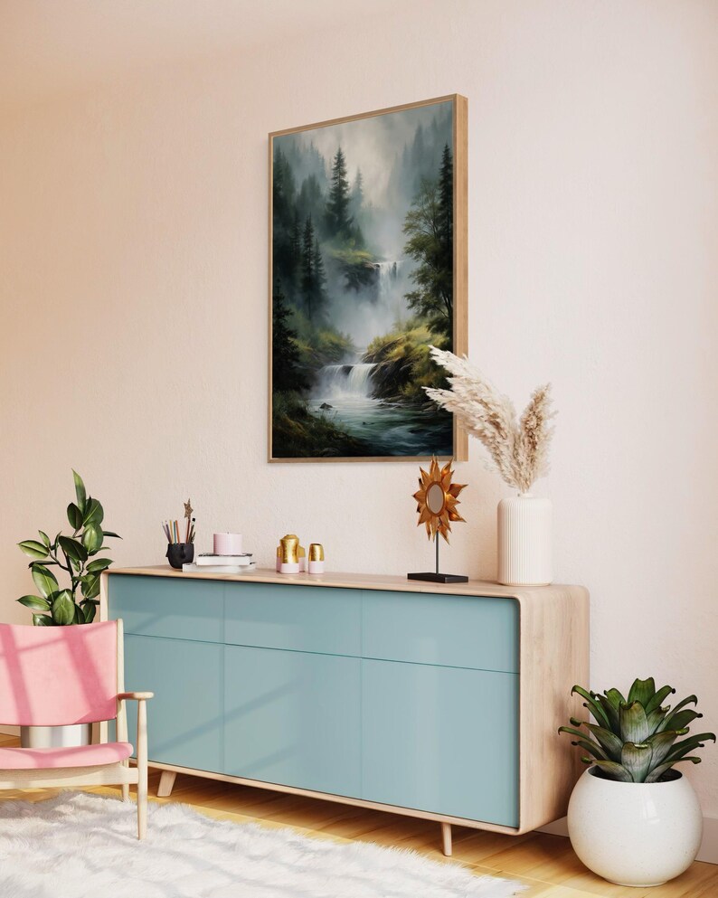 May include: A light blue dresser with three drawers and a wood top. The dresser is in a living room with a painting of a waterfall in a forest, a potted plant, and a decorative sun sculpture.