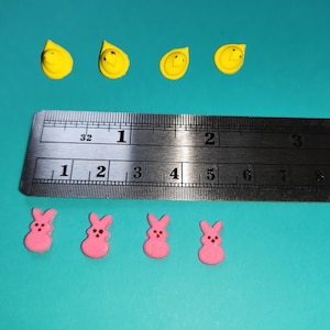 May include: A ruler with inch markings and four yellow chick-shaped candies and four pink bunny-shaped candies.