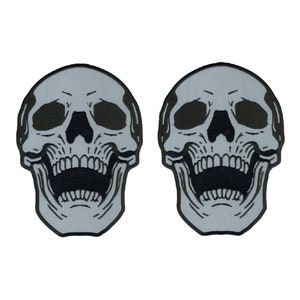 May include: Two gray skull patches with black details. The skulls are grinning with their mouths open and teeth showing.