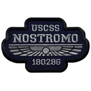 May include: A navy blue embroidered patch with the text "USCSS NOSTROMO" and the number "180286". The patch features a stylized winged design.