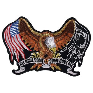 May include: An embroidered patch featuring a bald eagle with wings spread, holding a banner that reads "All Gave Some Some Gave All". The eagle is perched on a banner with the words "POW-MIA" and a silhouette of a soldier's helmet. The patch is on a black background.