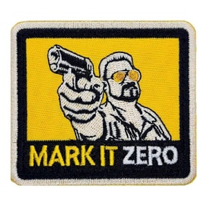 May include: A yellow and black embroidered patch with a cartoon image of a man wearing sunglasses and holding a gun. The text "MARK IT ZERO" is below the image.