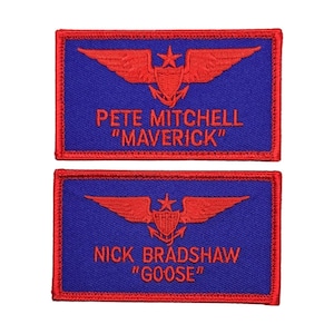 May include: Two rectangular patches with red embroidered text and design on a blue background. The top patch reads "PETE MITCHELL 'MAVERICK'" and the bottom patch reads "NICK BRADSHAW 'GOOSE'". Each patch features a red emblem of wings, a star, and a shield.