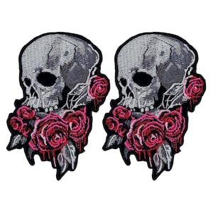 May include: Two embroidered iron-on patches featuring a skull with pink roses. The skull is gray and the roses are pink with black outlines.