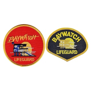 May include: Two embroidered patches with the words "Baywatch Lifeguard" in yellow lettering on a red and black background. The red patch has a stylized lifeguard stand with a sun and waves in the background. The black patch has a more realistic lifeguard stand with a sun and waves in the background.