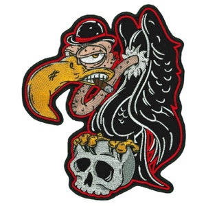 May include: A black and white embroidered patch of a cartoon vulture wearing a bowler hat and smoking a cigar, perched on a skull. The vulture has a yellow beak and red eyes. The patch has a red outline.