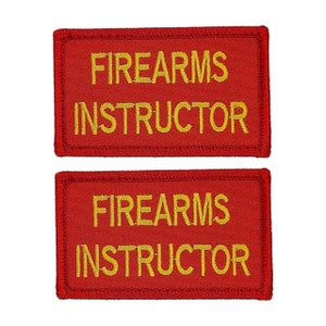 May include: Two red rectangular patches with yellow embroidered text that reads "FIREARMS INSTRUCTOR".