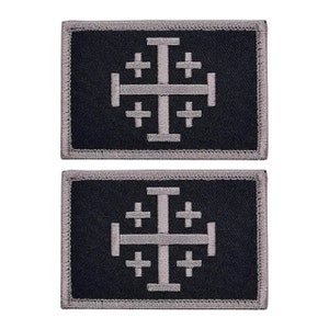 May include: Two black and gray embroidered patches with a white cross design. The cross is a Jerusalem cross with four smaller crosses at the ends of the arms.