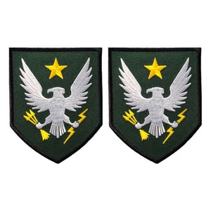 May include: Two green and black embroidered patches with a white eagle, a yellow star, and yellow lightning bolts.