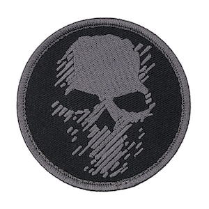 May include: A black and gray embroidered patch with a skull design. The skull is outlined in gray and has a black background.