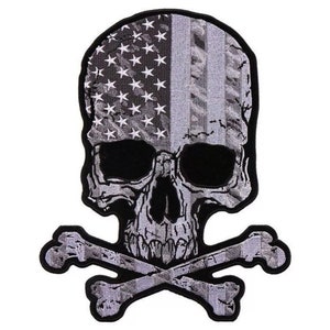 May include: A black and white embroidered patch of a skull and crossbones. The skull is covered in a gray and white American flag design.
