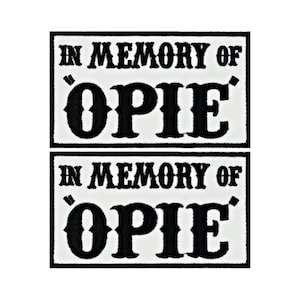 May include: Two white rectangular patches with black embroidered text. The text reads "In Memory of 'OPIE'".