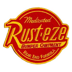 May include: Embroidered patch with the text "Medicated Rust-eze Bumper Ointment Rear End Formula" in yellow on a red background. The patch has a rounded shape with a yellow border.
