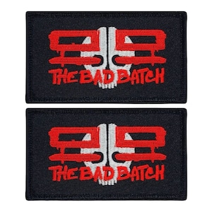 May include: Two black embroidered patches with red and white details. The patches feature a skull with the text "THE BAD BATCH" underneath.