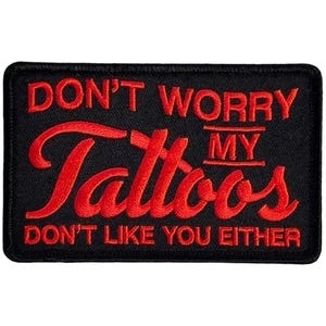 May include: Black rectangular patch with red embroidered text that reads "DON'T WORRY MY Tattoos DON'T LIKE YOU EITHER". The patch has a black border and is likely made of fabric.