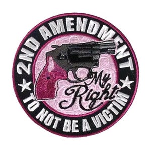 May include: A black and white embroidered patch with a pink handgun and the text "2nd Amendment My Right To Not Be A Victim".