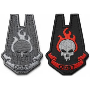 May include: Two embroidered patches, one gray and one black, each featuring a skull design with flames and the text "ODST". The gray patch has a silver skull and flames, while the black patch has a white skull and red flames.