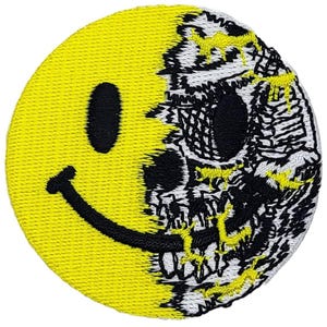 May include: A yellow smiley face with a black outline is partially obscured by a black and white skull. The skull is cracked and broken, revealing the yellow smiley face underneath.