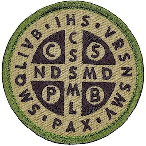 May include: A round, beige patch with a green border. The patch features a brown cross with the letters "C.S.P.M.B." in the center. The letters "I.H.S." are above the cross, and the letters "V.R.S.N.S." are below the cross. The letters "O.L.I.V.B." are to the left of the cross, and the letters "A.W.S.P.A.X." are to the right of the cross.