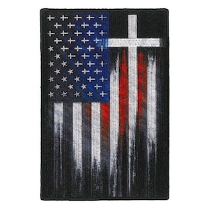May include: A black and white embroidered patch with a faded American flag design. A white cross is superimposed over the flag, with the red stripes of the flag showing through the cross.