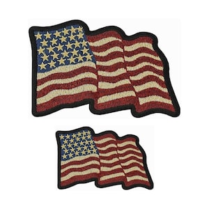 May include: Two embroidered American flag patches. The larger patch is a waving flag with red and white stripes and blue stars. The smaller patch is a similar design but smaller in size.