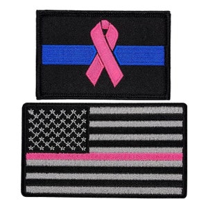May include: Two embroidered patches. The top patch is black with a blue stripe and a pink ribbon. The bottom patch is a black and white American flag with a pink stripe.