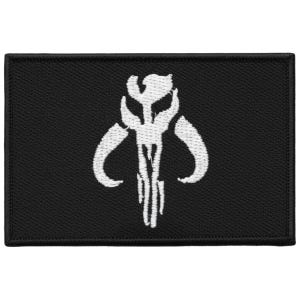 May include: A black rectangular patch featuring a white emblem. The emblem is a stylized skull with curved horns and vertical lines. The patch is likely an embroidered or woven design.
