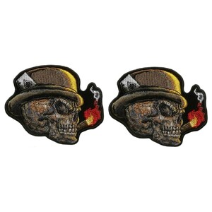 May include: Two embroidered iron-on patches featuring a skull wearing a top hat and smoking a cigar. The skull has a gold tooth and the cigar is lit with red and yellow flames.