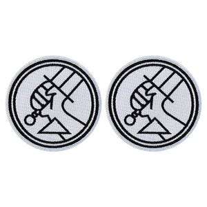 May include: Two black and white embroidered iron-on patches featuring the "Watchmen" logo. The logo is a stylized fist holding a sword with a triangle underneath.