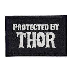 May include: Black embroidered patch with white text that reads "PROTECTED BY THOR" with a lightning bolt in the "O".