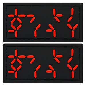 May include: Two black patches with red, white, and blue symbols. The symbols are arranged in a pattern that resembles a code or a message.