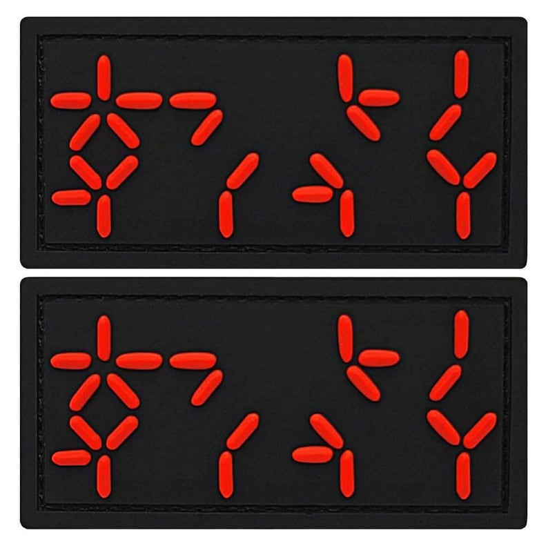 May include: Two black patches with red, white, and blue symbols. The symbols are arranged in a pattern that resembles a code or a message.