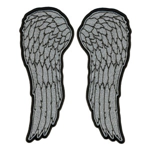 May include: A pair of silver embroidered angel wings with black outlines. The wings are a popular design for motorcycle jackets and vests.