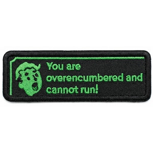 May include: Black rectangular patch with green embroidered text and a green cartoon character. The text reads "You are overencumbered and cannot run!" The patch has a black border and a white background.