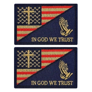 May include: Two blue patches with an American flag design. The flag is split diagonally with the top half being the American flag and the bottom half being a dark blue background. The flag has a gold cross and the words "In God We Trust" in gold lettering. The patches are for sewing or ironing onto clothing.