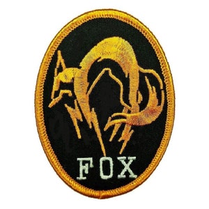 May include: A black and gold embroidered patch with a stylized fox design and the word "FOX" in white lettering.