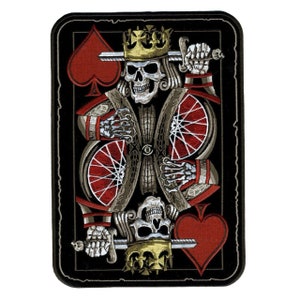 May include: A black and red embroidered patch featuring a skeleton king of spades holding a sword. The king is wearing a gold crown and has a red heart in the background.