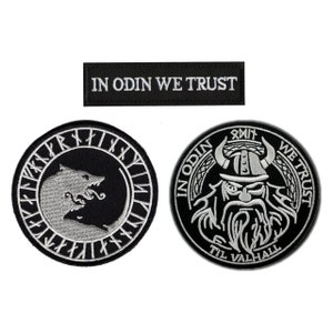 May include: Three black and white embroidered patches. One rectangular patch reads "IN ODIN WE TRUST". Two circular patches feature Viking imagery, including a wolf and Odin with the text "IN ODIN WE TRUST" and "TIL VALHALL".