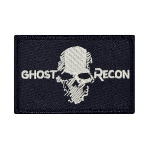 May include: A black embroidered patch with a white skull and crossbones design. The text "Ghost Recon" is embroidered in white below the skull.