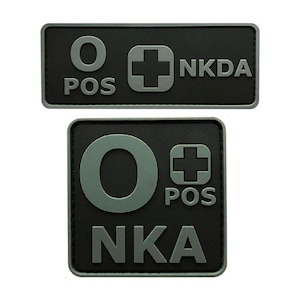 May include: Two black and gray patches with white text. The top patch reads "O POS NKDA" and the bottom patch reads "O POS NKA".