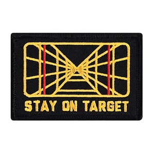 May include: Black embroidered patch with a yellow and red graphic of a targeting system and the text "STAY ON TARGET".