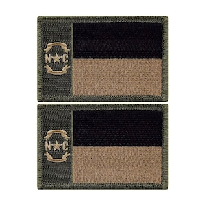 May include: Two green embroidered patches with a brown and black North Carolina flag design. The flag features a star in a circle with the letters "N" and "C" on either side of the star. The patches are approximately 3 inches by 2 inches.