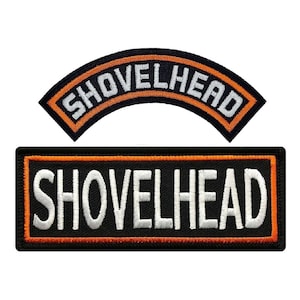 May include: Two embroidered patches with the text "SHOVELHEAD" in white lettering on a black background. The top patch is curved and has an orange border. The bottom patch is rectangular and has an orange border.