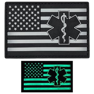 May include: A black and white American flag patch with a white medical symbol, a star of life with a snake, in the upper right corner. The patch glows green in the dark.
