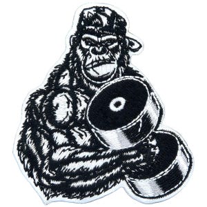 May include: Embroidered patch featuring a gorilla wearing a cap and holding a dumbbell. The patch is black and white with detailed stitching, showcasing the gorilla's face and fur. The dumbbell is also black and white.