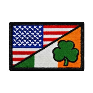 May include: An embroidered patch with the American flag and the Irish flag, with a shamrock in the Irish flag. The patch is black with white stitching around the edges.