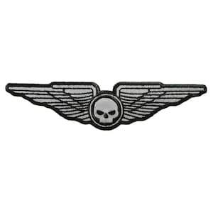 May include: A black and white embroidered patch with a skull and wings. The wings are silver and the skull is white with black eyes.